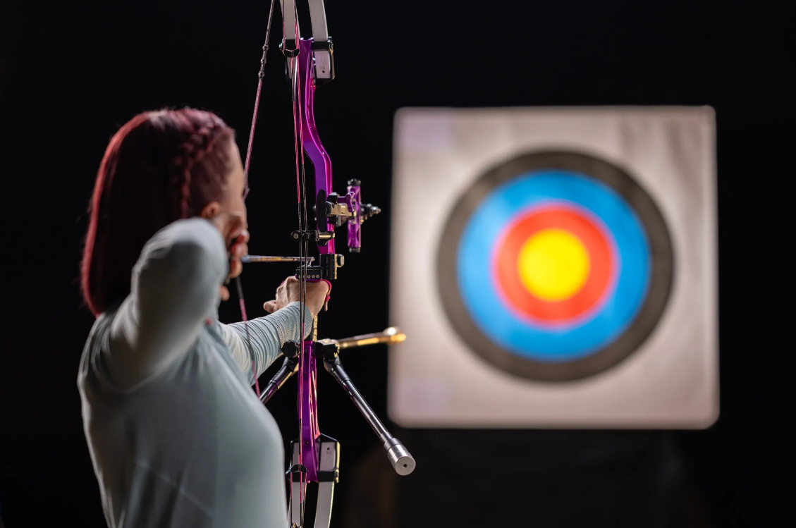 Woman aiming a compound bow at the archery range
