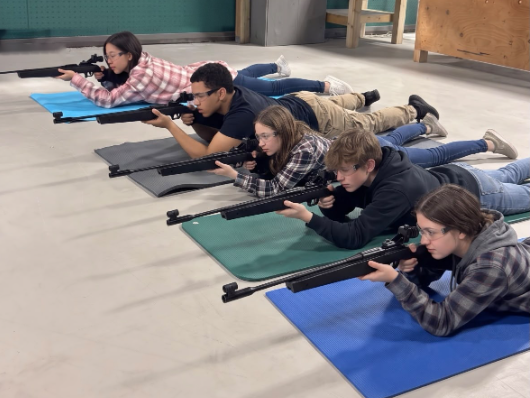 Young shooter in the prone position aiming an air rifle